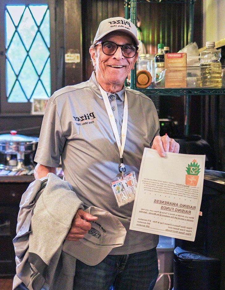 an alum holds up a giving flier in the grove house